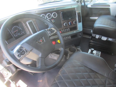 Western Star 47X truck interior showing steering wheel with W emblem, instrument cluster, large center touchscreen, climate controls, and diamond-stitched seat.