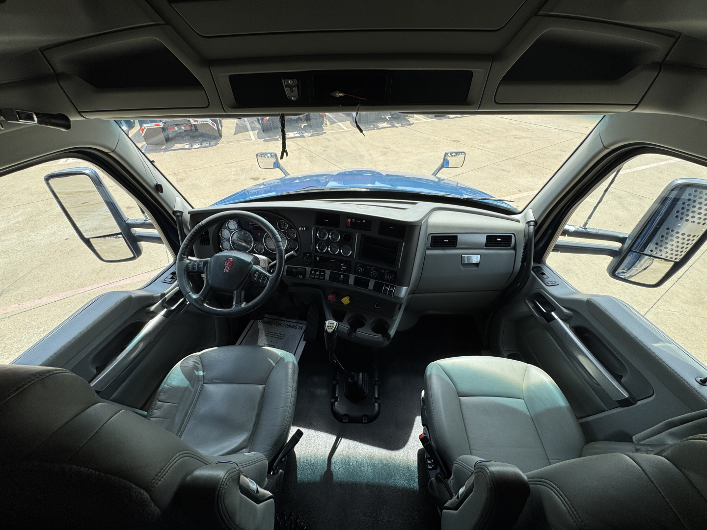 Kenworth T880 truck interior cab view showing steering wheel, dashboard, front seats, and dual consoles.