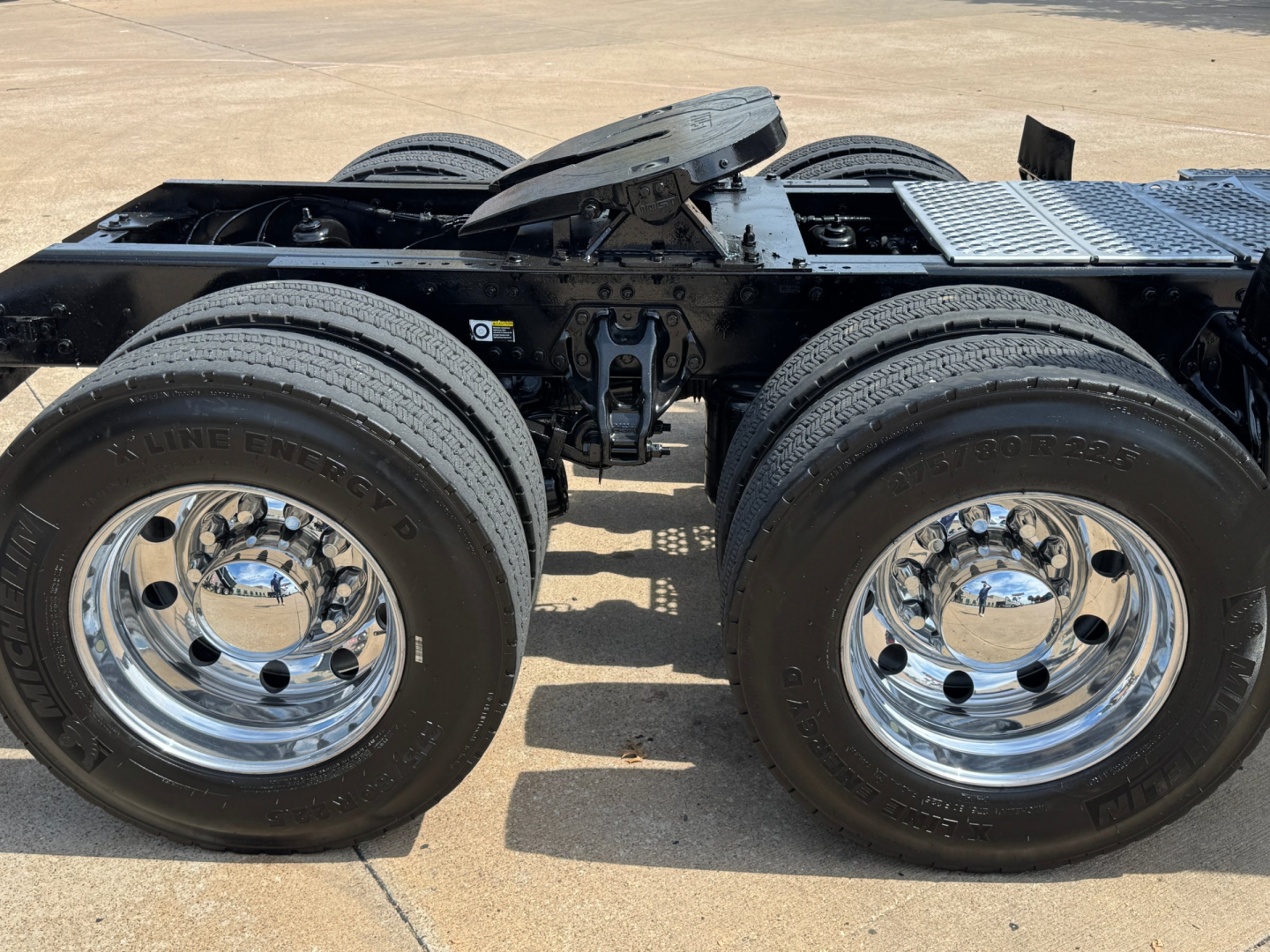 Kenworth T880 chassis with dual rear axles and dual tires, chrome wheels, viewed from side showing fifth-wheel area and frame.