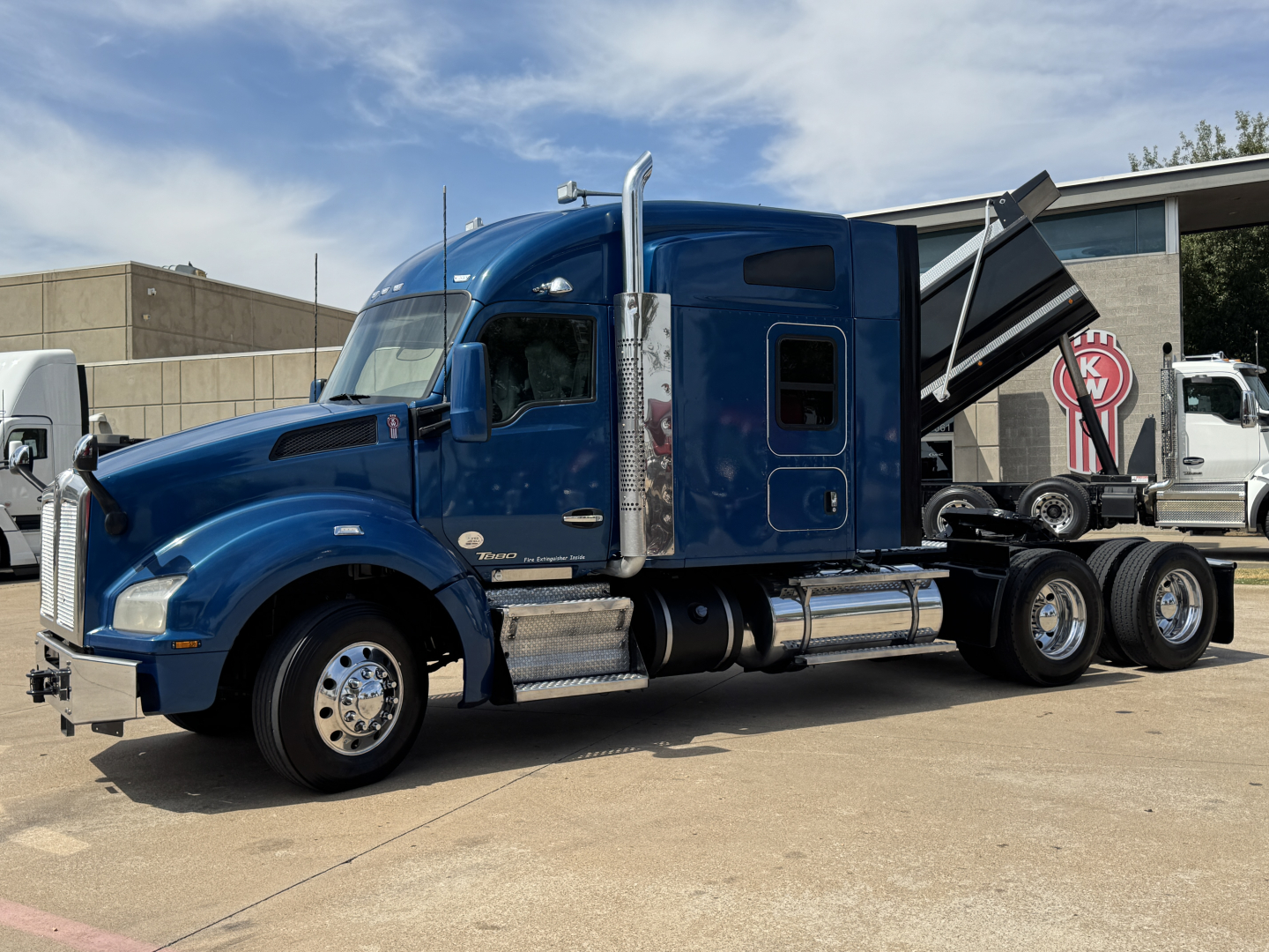 Kenworth T880 conventional sleeper tractor in blue, side view, with dumping trailer bed visible.