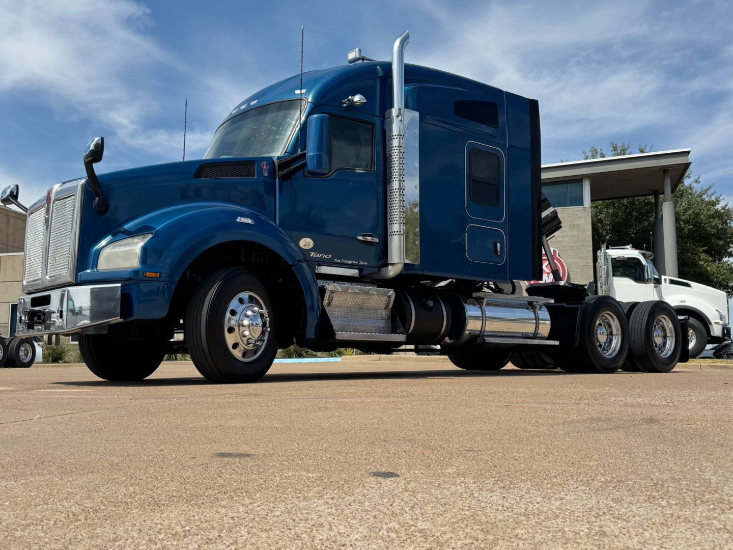 Kenworth T880 conventional sleeper truck in blue, side view showing fuel tanks and steps.