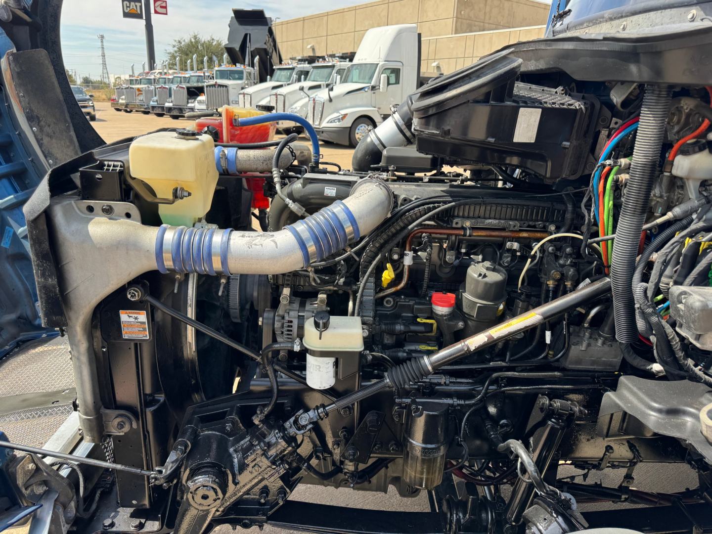 Engine bay of a 2019 Kenworth T880 conventional sleeper showing exposed diesel engine, hoses, wiring, and components.