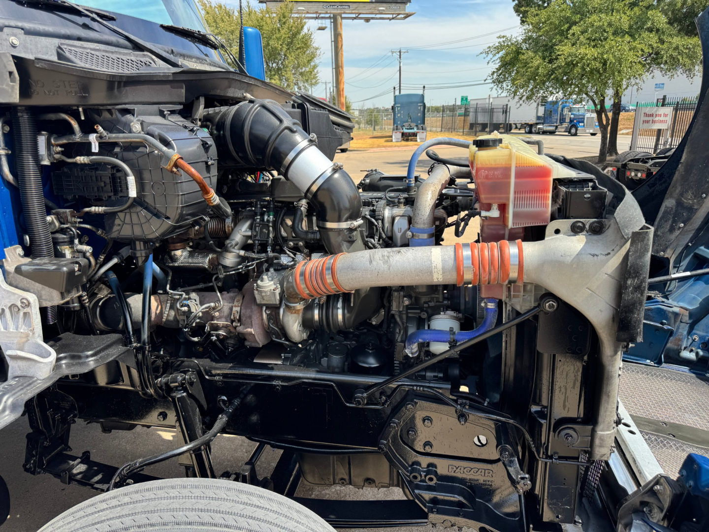 Kenworth T880 engine bay with intake piping, coolant reservoir, and radiator area visible; side view showing engine components and frame.
