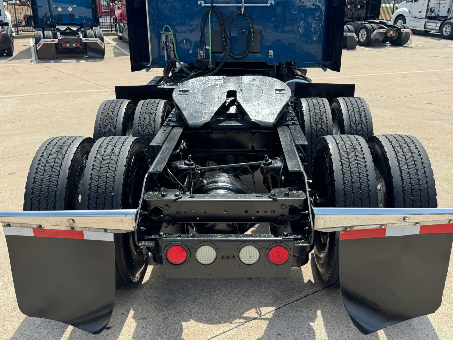 Kenworth truck rear showing fifth wheel and dual rear axles with mudflaps and lights; no visible model text or stickers readable.