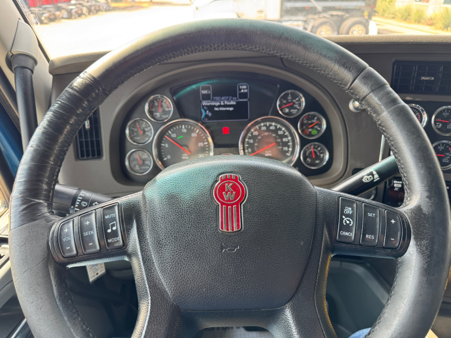 Kenworth T880 steering wheel and instrument cluster showing gauges and controls, on-time display visible in center, with multiple analog gauges.