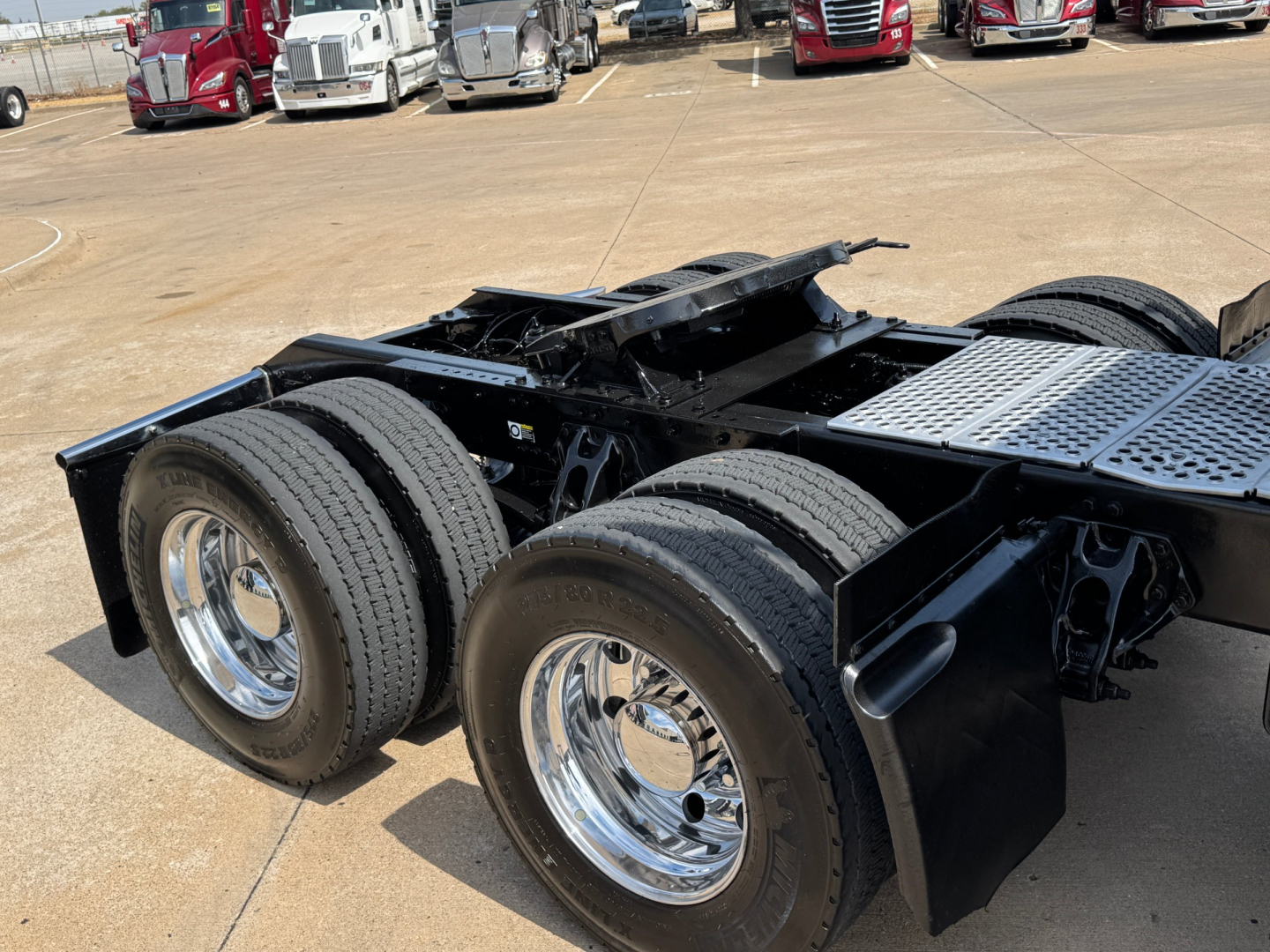 Kenworth truck trailer chassis showing dual rear axles with chrome wheels and heavy-duty frame.