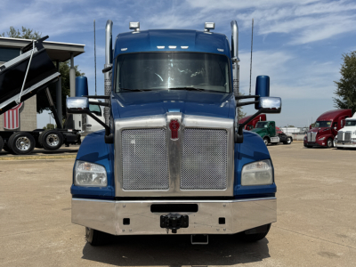Kenworth T880 conventional sleeper truck front view showing large chrome grille, blue cab, black bumper, and two chrome horns; side mirrors and sun visors visible.