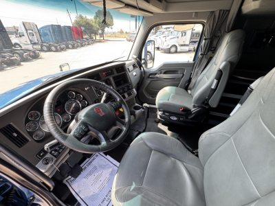 Kenworth T880 truck interior showing steering wheel, dashboard, and two front seats; cab interior with grey upholstery and control panels visible.
