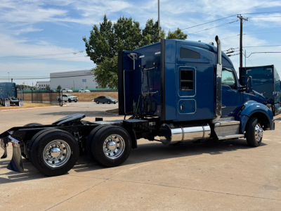Kenworth T880 semi-truck tractor in blue, side view showing sleeper cab, fuel tanks, and rear dual axles.