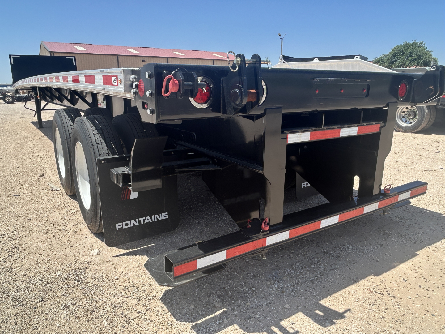 Flatbed trailer showing Fontaine branding and dual rear tires with deck and safety rails.