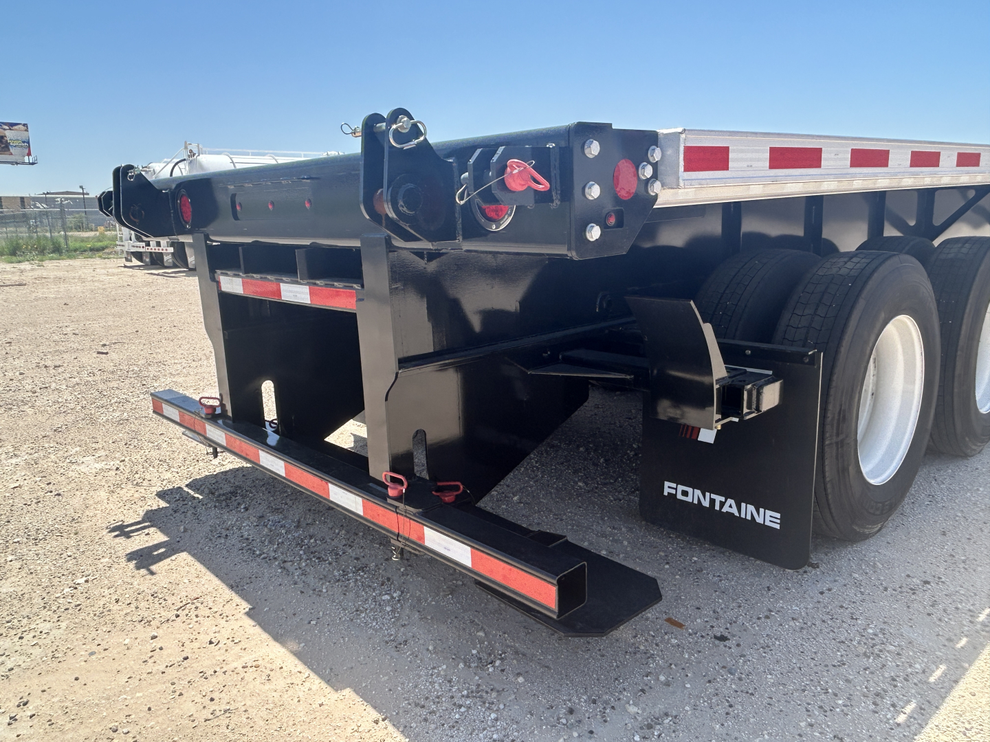 Fontaine HCIFL12SAT flatbed trailer rear view showing black frame, dual rear axles, and side safety light blocks with Fontaine branding.