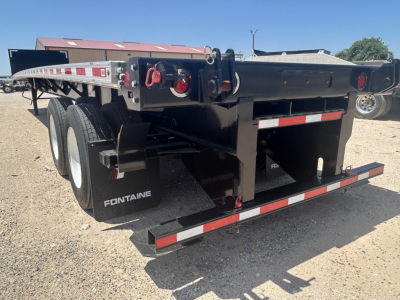 Flatbed trailer showing Fontaine branding and dual rear tires with deck and safety rails.
