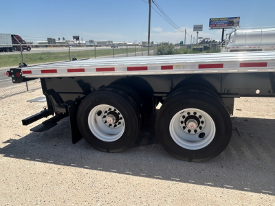 Flatbed trailer wheel area showing tandem axles and white rims, Fontaine HCIFL12SAT trailer model badge not visible.