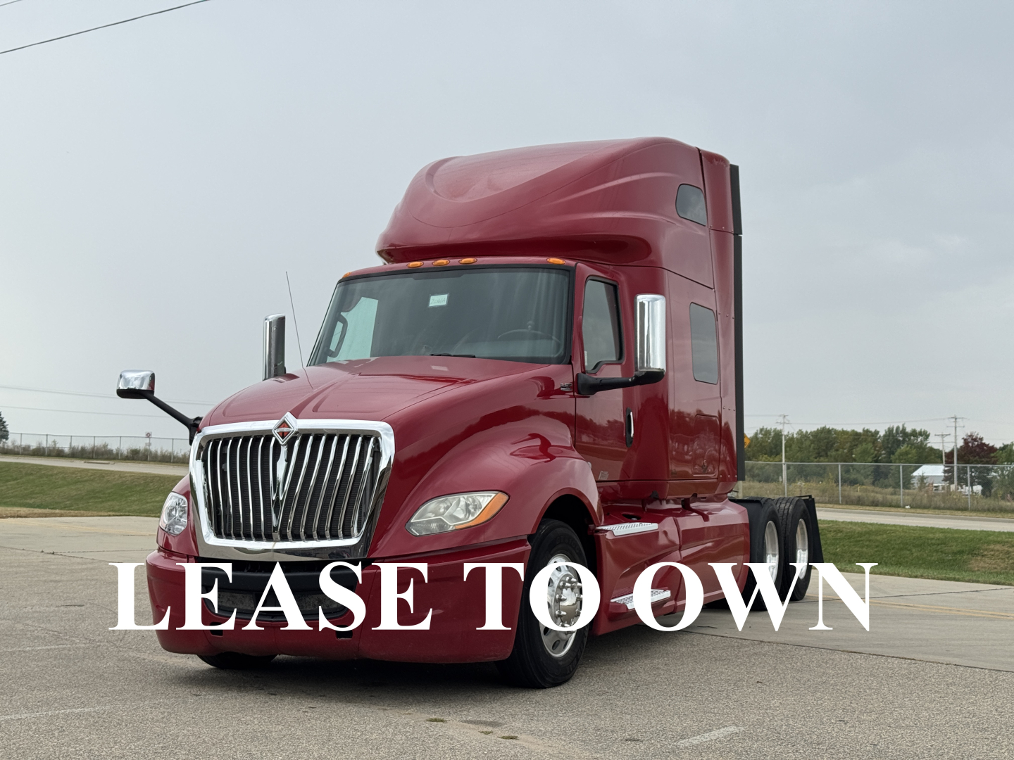 2018 International LT625 sleeper truck in maroon, front-left view with large chrome grille and hood; white text overlays say 'LEASE TO OWN' across image.
