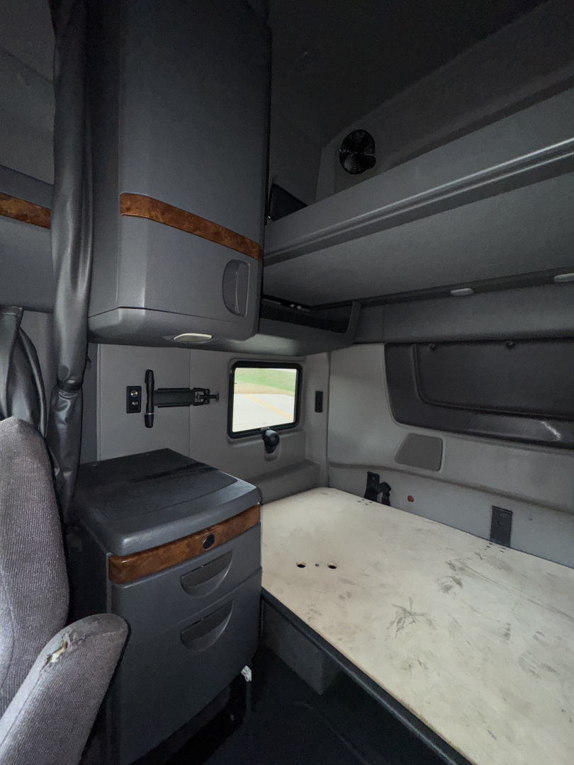 Cab interior of a 2018 International LT625 sleeper showing bunk bed area and storage cabinet.