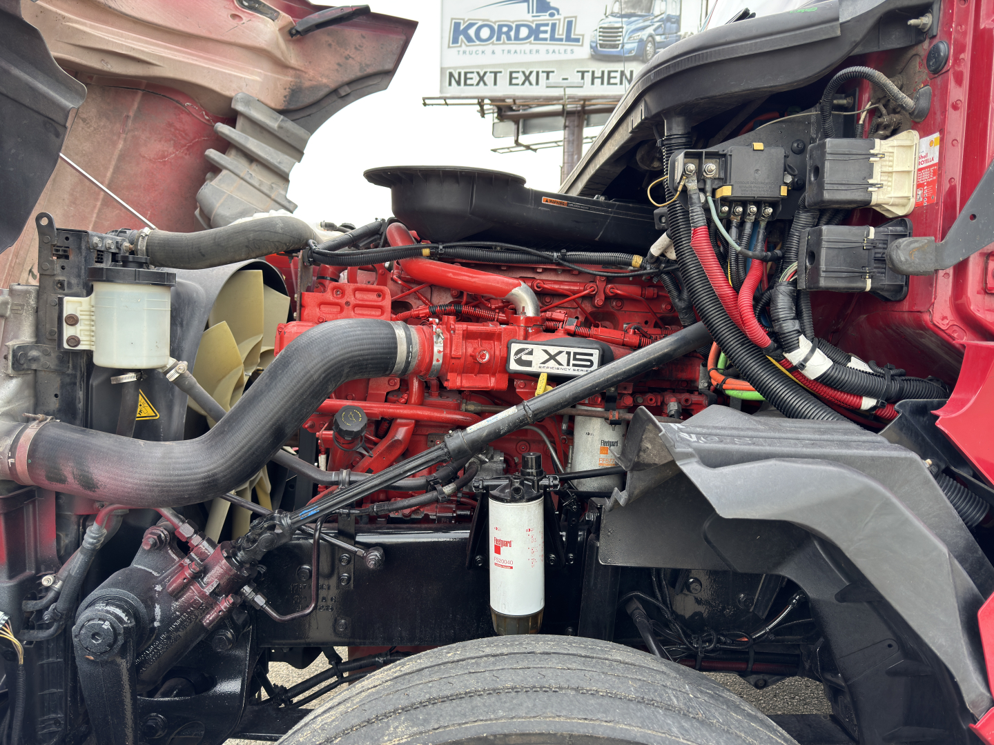 International LT625 engine bay showing red engine block with 'EXIS' badge, hoses, air filter canister, and wiring harness visible.