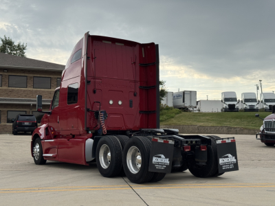 Truck rear view of a red 2018 International LT625 sleeper with triple rear axles and black chassis, showing no visible text on side; photo taken in a dealership lot.