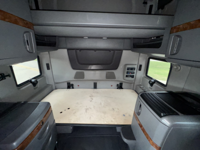 Interior of a used 2018 International LT625 sleeper cab showing cargo area with flat plywood floor and side cabinets.