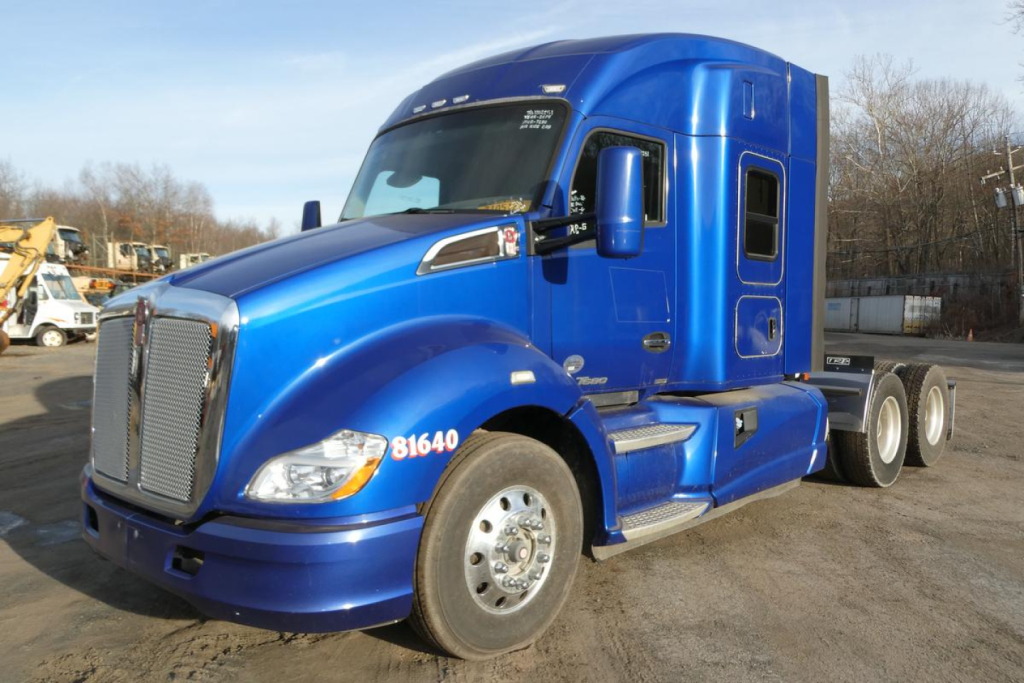 Kenworth T680 truck in blue, front three-quarter view, showing cab with sleeper, dual rear axles, chrome grille and headlights.