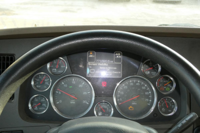 Kenworth T680 dash cluster and steering wheel showing gauges and digital screen in center.