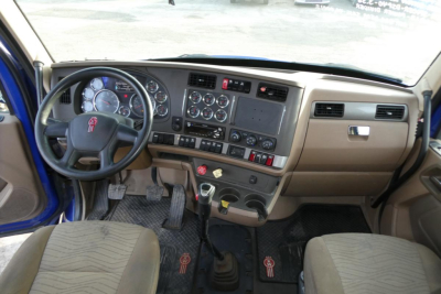 Kenworth T680 truck interior dashboard and steering wheel with pedals and gear shifter.