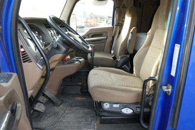 Kenworth T680 cab interior showing dashboard steering wheel and tan cloth seats
