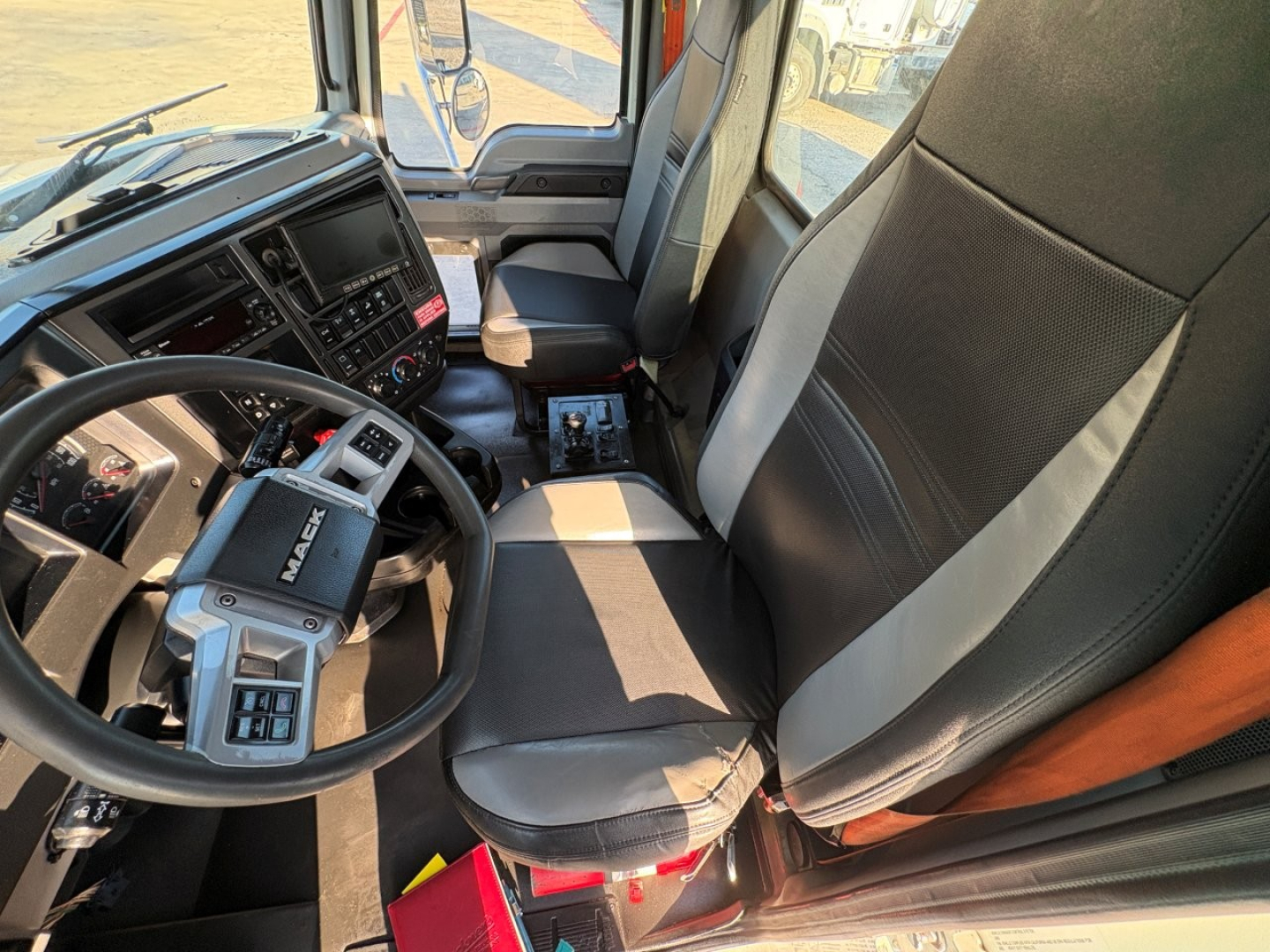 Cab interior of a 2023 Mack GR84F dump truck showing steering wheel, dashboard, and two front seats.