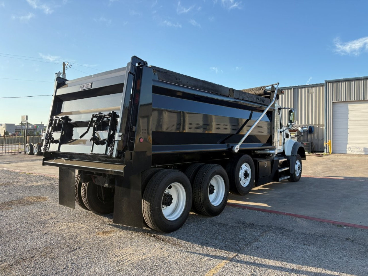 Dump truck with Mack GR84F dump body showing side profile and rear view with dual rear wheels and black and blue paint.