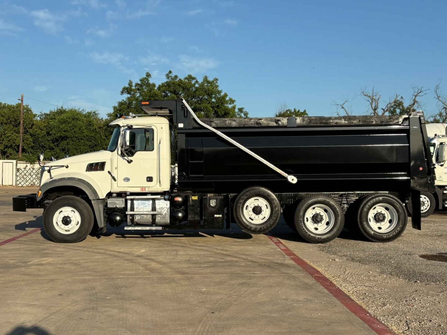 Dump truck side view showing Mack GR84F with black dump body, white cab, and multiple wheels. VIN plate not visible.