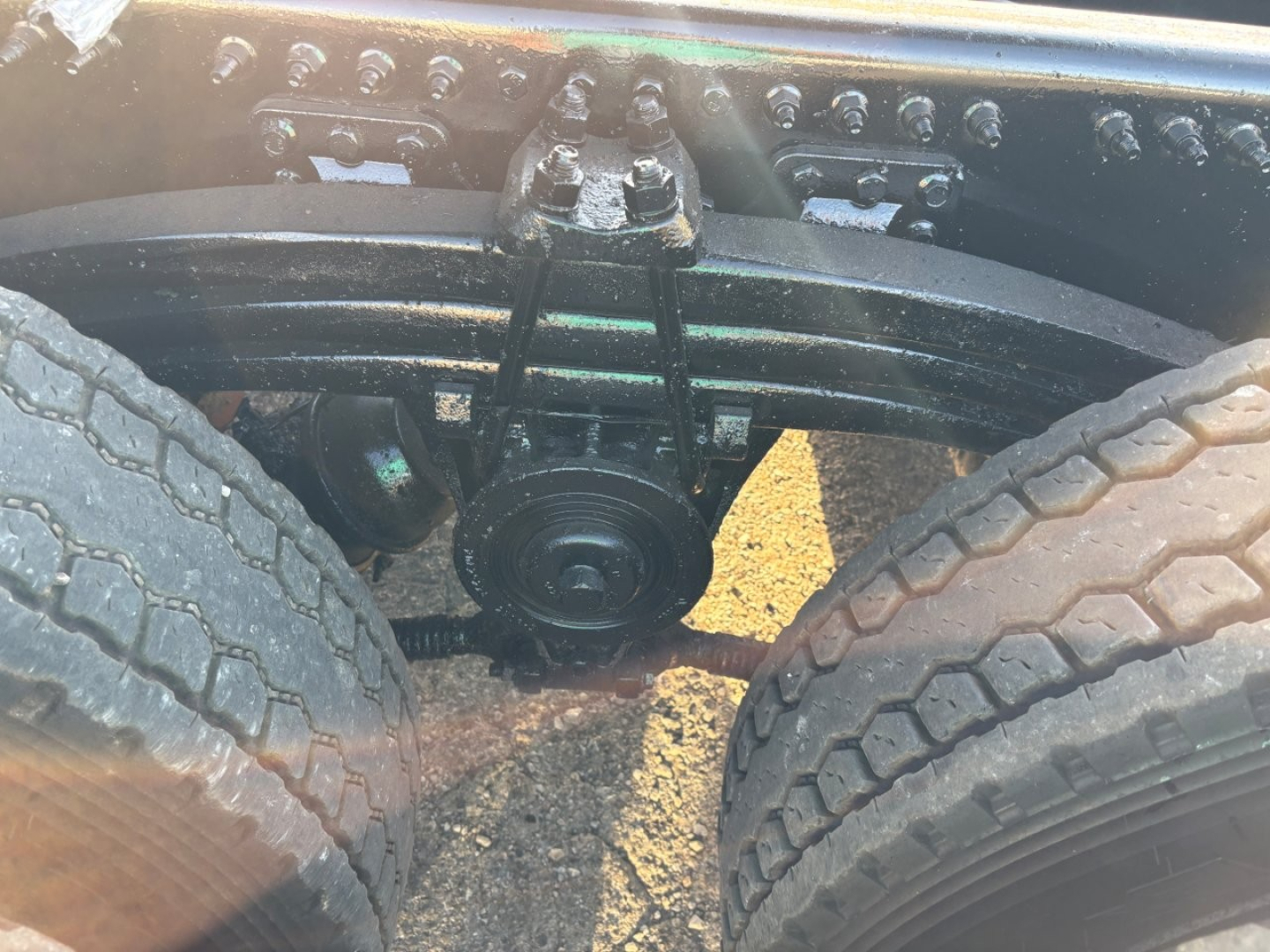 Axle housing and twin rear tires of a Mack GR84F dump truck showing drivetrain components and suspension near the wheel area.
