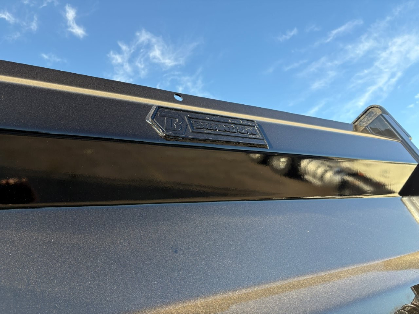 Truck hood badge area showing Mack logo emblem on a GR84F dump truck, blue sky reflection, close-up of front end