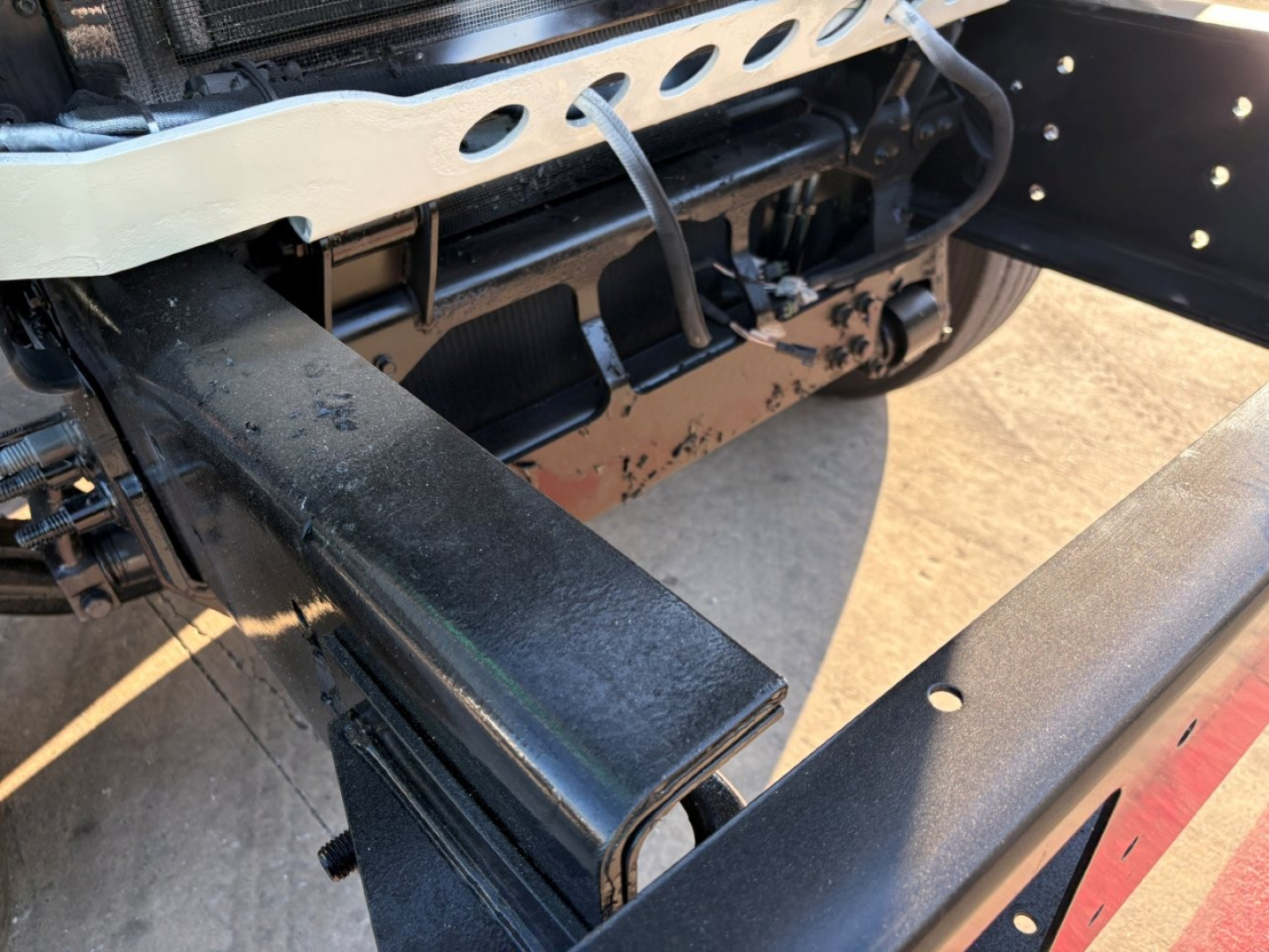 Mack GR84F chassis area with black metal frame and beige protective guard; visible components include a rectangular crossmember and mounting brackets.