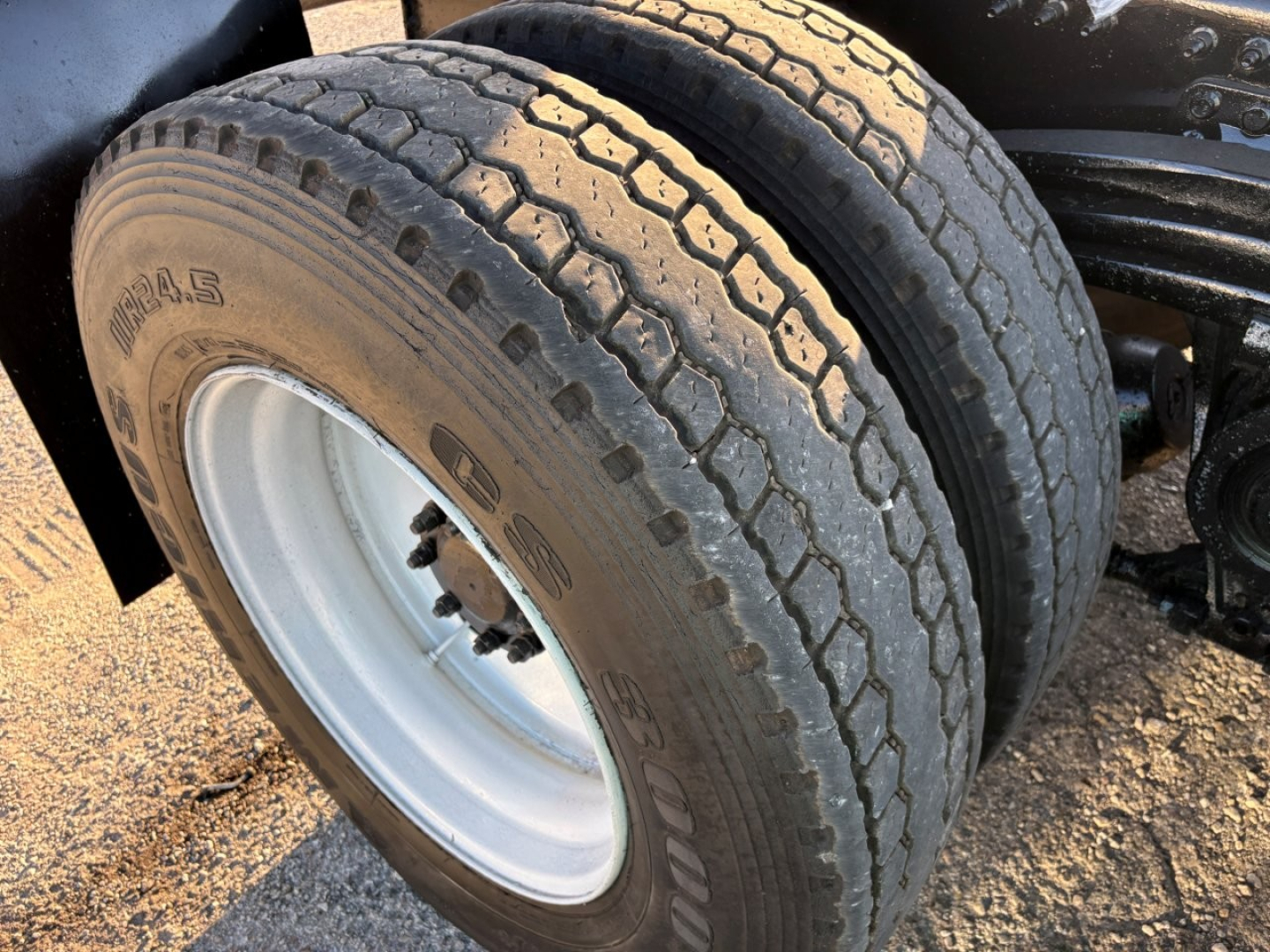 Dual rear tires on Mack GR84F dump truck showing heavy-duty tire treads and white steel rims.