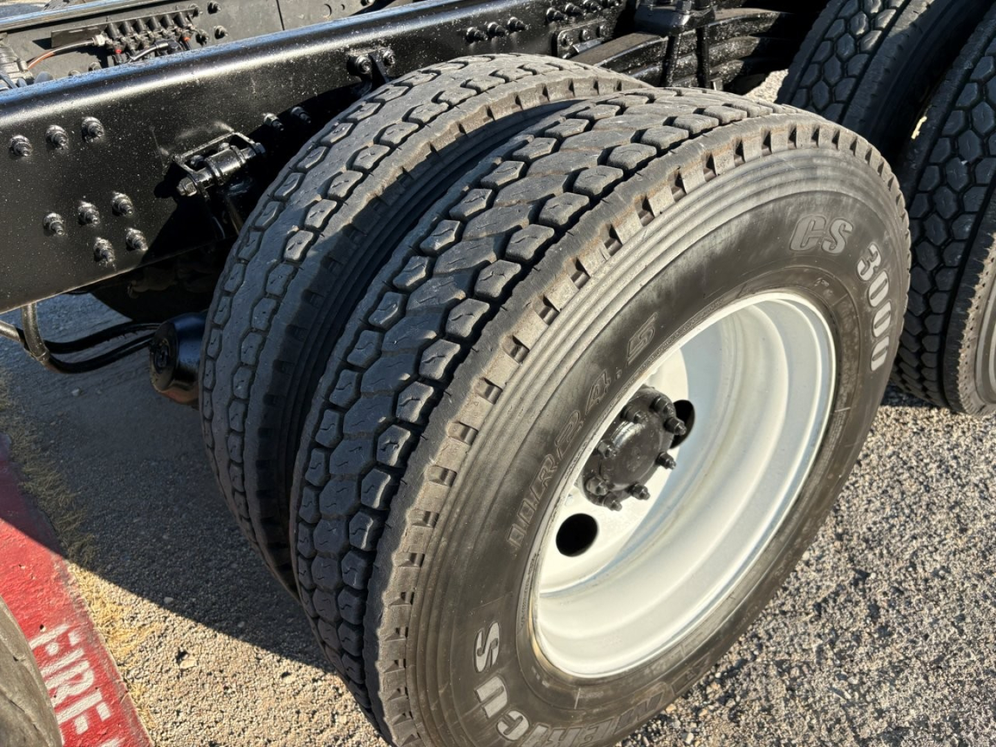 Dual rear wheels on a Mack GR84F dump truck showing heavy-duty tires and white steel rims.