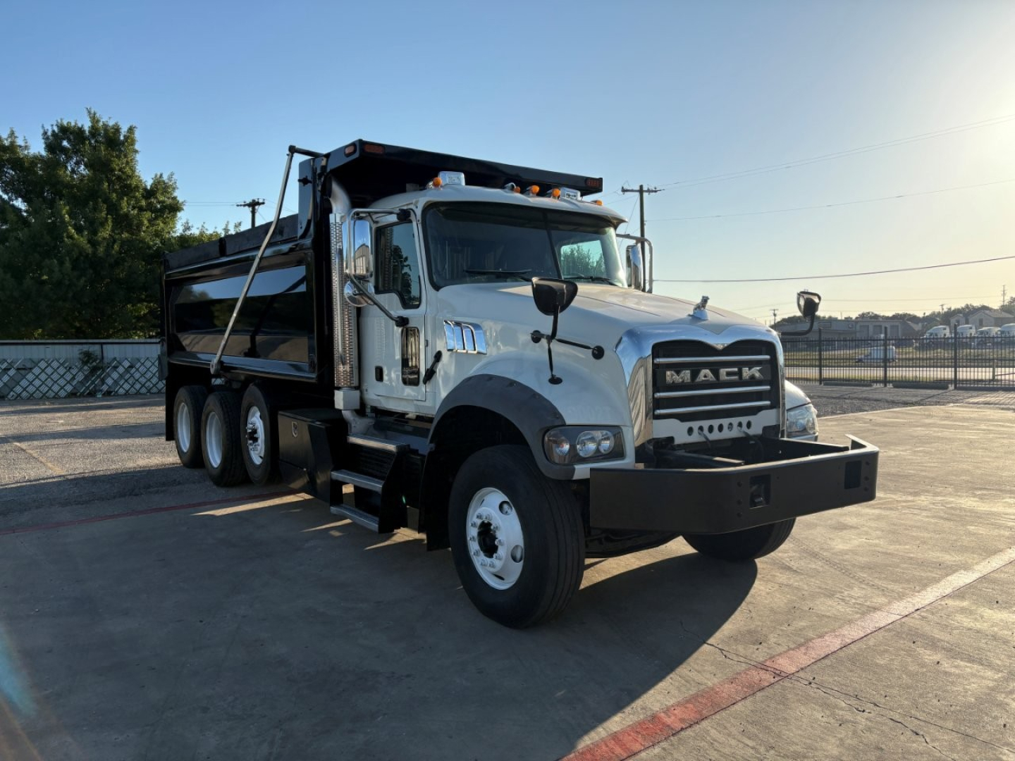 Dump truck showing a white Mack GR84F dump truck with black grille, three-axle rear, and large front bumper.