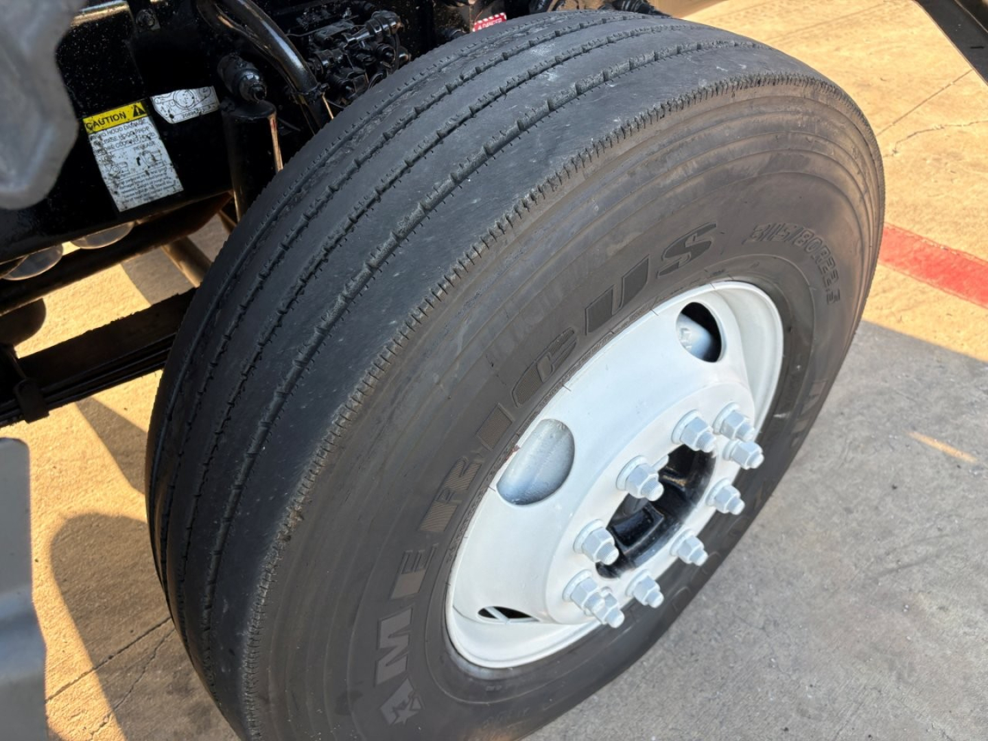 Wheel and tire close-up with dual rear axle hub on a Mack GR84F truck; shows tire sidewall and white steel wheel with lug nuts.