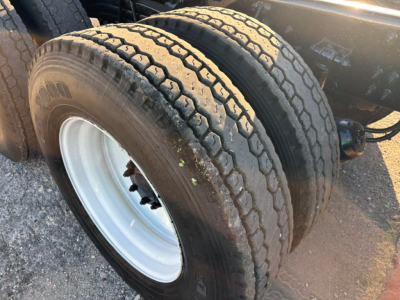Tandem rear axle with dual tires on a Mack GR84F dump truck showing tread and white wheel.