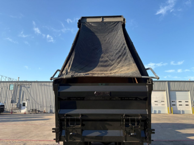 Dump truck bed with raised hydraulic tarp and open tail gate on a Mack GR84F chassis, black paint, clear blue sky in background.