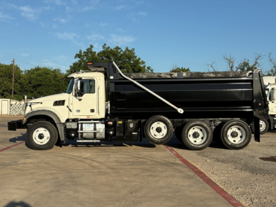 Dump truck side view showing Mack GR84F with black dump body, white cab, and multiple wheels. VIN plate not visible.