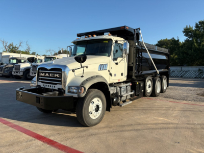 Mack GR84F dump truck showing front grille and cab with dump bed in a parking lot.