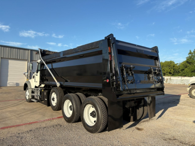Dump truck rear and side view with black dump body and chassis, Mack GR84F with triple rear axles visible.