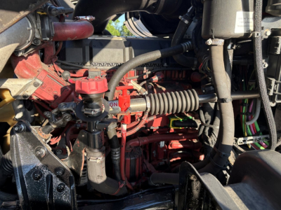 Mack GR84F engine bay showing red-painted engine block, hoses, and electrical harnesses with components like fuel injectors and intake tubing visible.