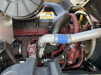 Engine bay of 2023 Mack GR84F dump truck showing red turbocharger, hoses, and intake pipe with blue hose clamp.