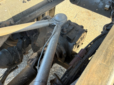 Mack GR84F truck front suspension/steering area showing hydraulic steering component and linkages with hoses and frame members.