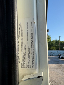 Vehicle information label on Mack GR84F side door area with small printed text including VIN and regulatory statements.