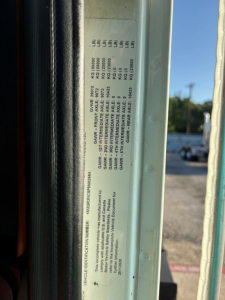 Mack GR64F (cab edge) information label with GVWR and tire data plates visible along door jamb.