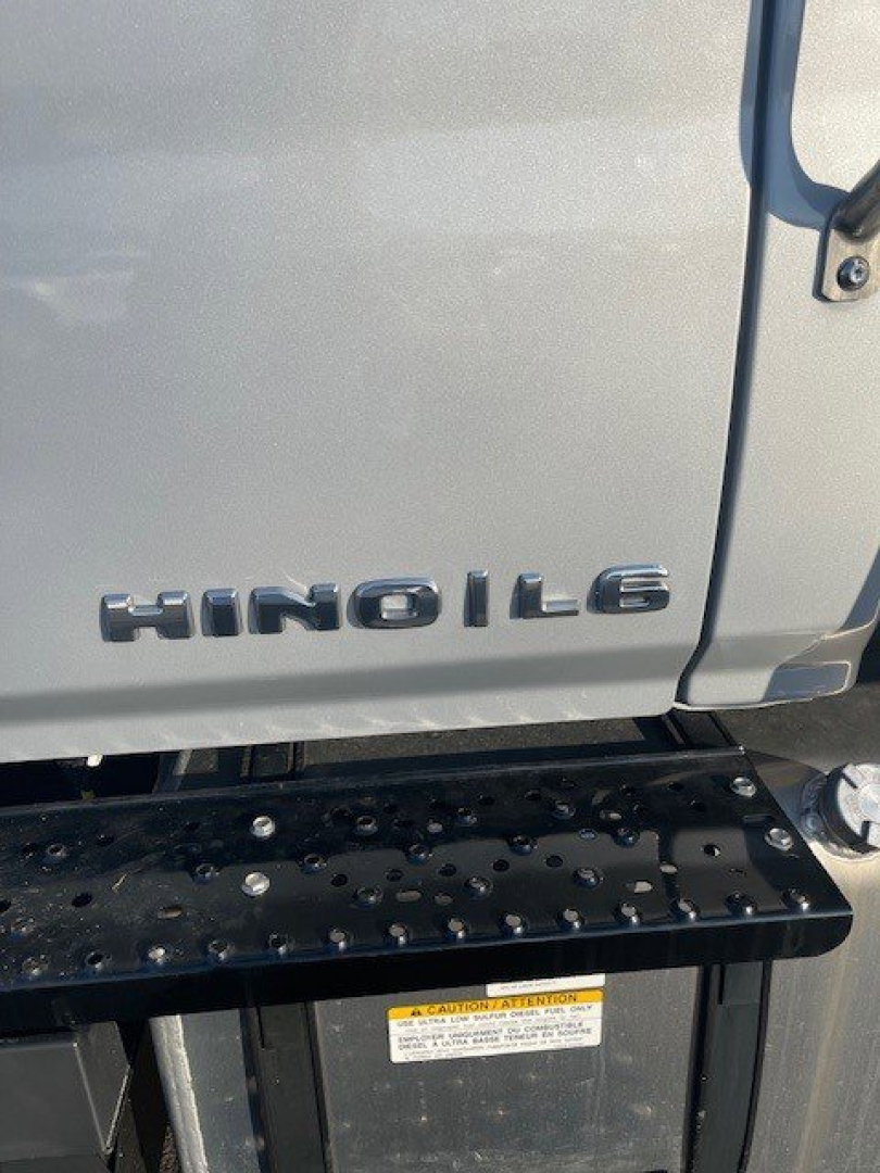 Hino L6 badge on door of box van truck with running board and yellow warning label visible.