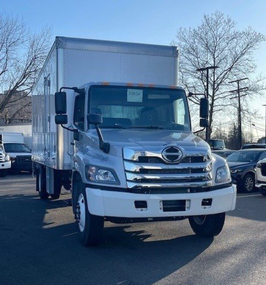 Box truck front view showing Hino cab with chrome grille and large side mirrors.