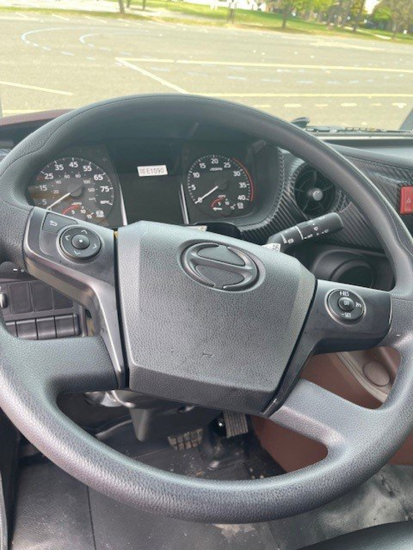 Steering wheel and dashboard of a Hino L6 truck cab showing instrument cluster and control stalks.