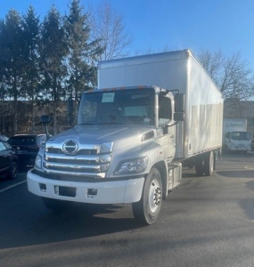 Box truck front-left view showing Hino cargo box, cab with chrome grille, Hino badge, and large side mirrors.